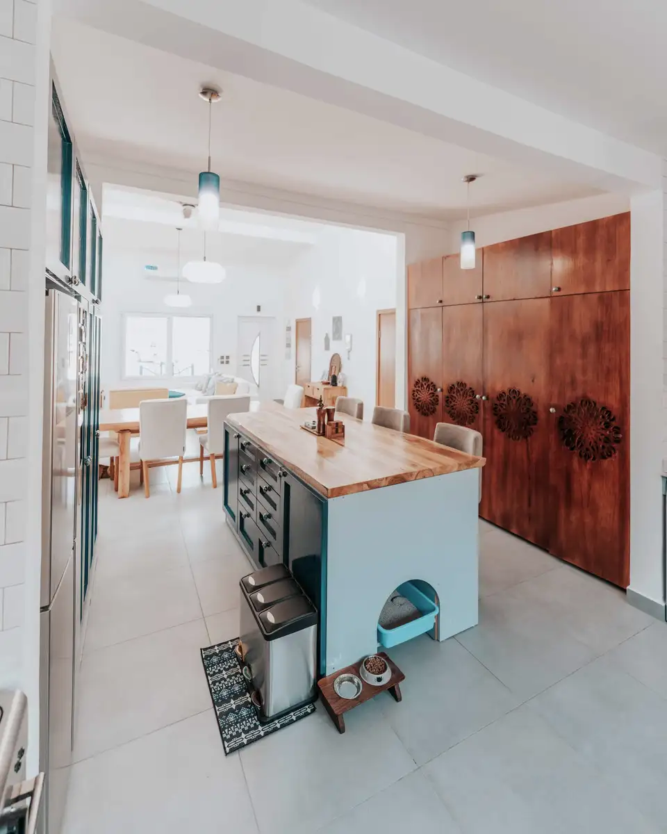 Finished kitchen with teal cabinetry, a butcher block island and the dining table beyond