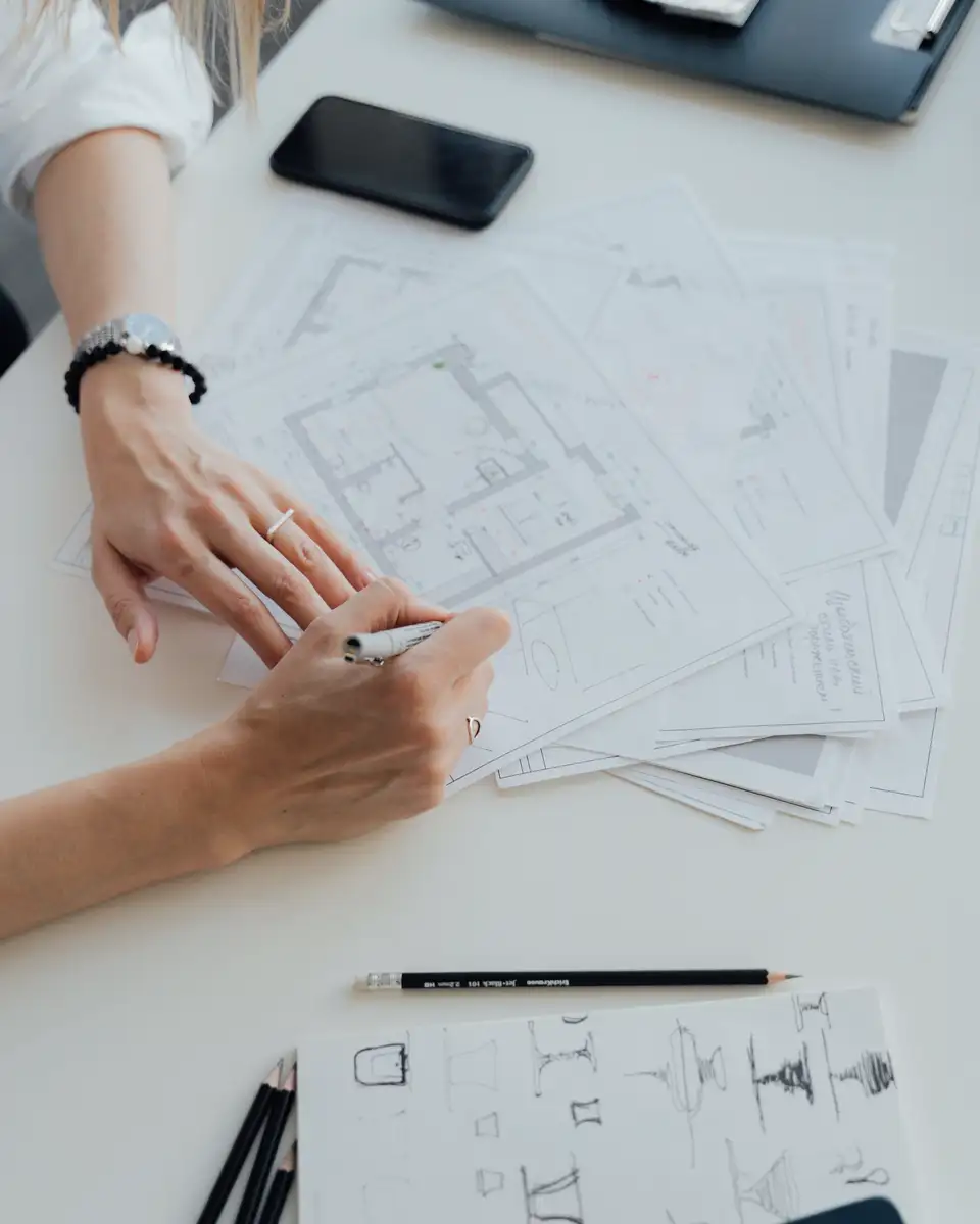 Designer's hands drafting a floor plan with a pencil